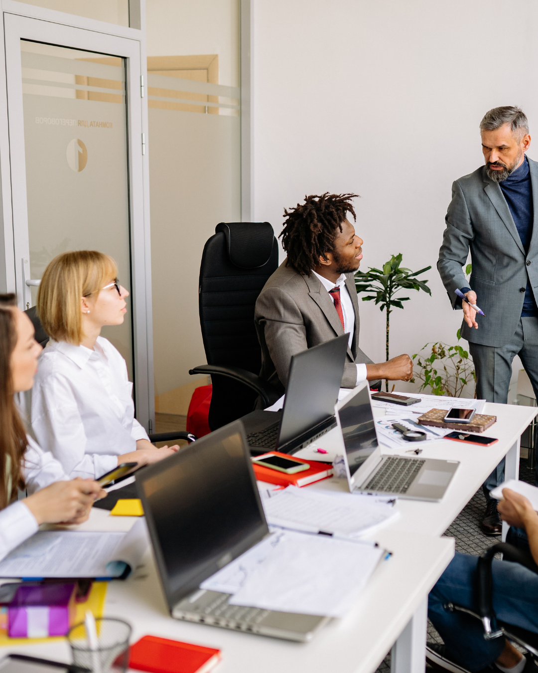 Several people in an office. Three people are sitting; one stands.