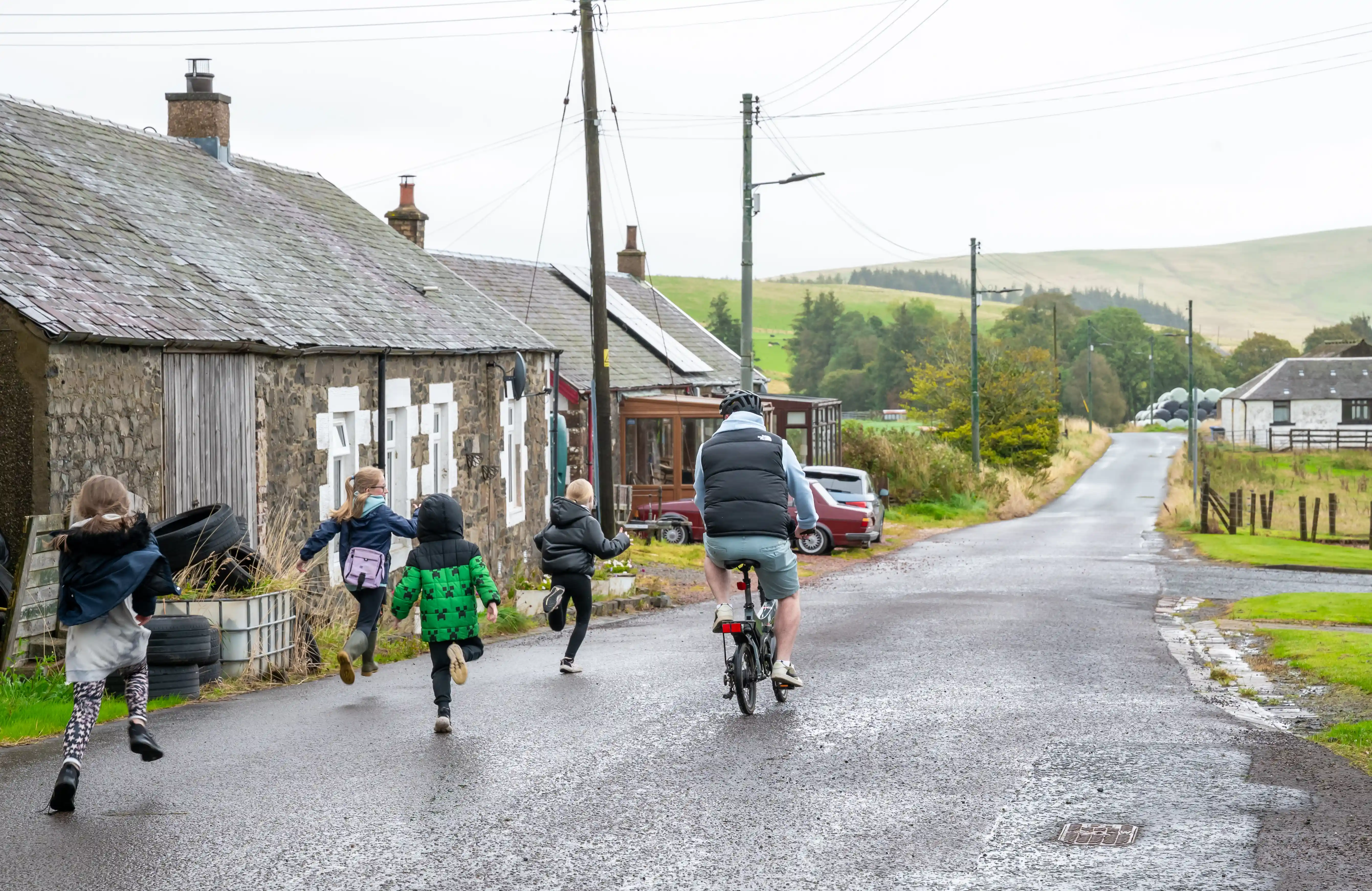 Kids running after man cycling on rural road at Lanarkshire Climate Action Festival 2024 - Photography by Lucy Knott